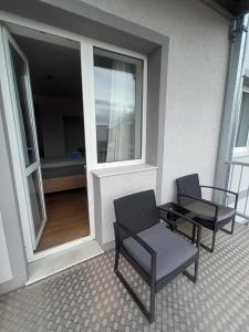Un balcón con dos sillas y una mesa y una ventana. en Schöne Wohnung mit WLAN und Balkon in Magdeburg Salbke, en Magdeburgo