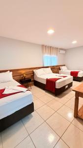 ein Hotelzimmer mit 3 Betten und einem Tisch in der Unterkunft Navega Beach House - Casa 2 Andares in Navegantes