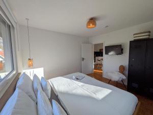 a white bedroom with a bed and a window at die Übernachterei in Hüfingen