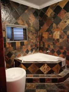 a bathroom with a bath tub and a toilet at Nelspruit Madiva Guest House in Nelspruit