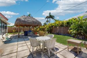 eine Terrasse mit Tisch und Stühlen und einem Strohschirm in der Unterkunft Shell Seeker in Bowmans Beach Helistop