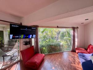 una sala de estar con una gran ventana y sillas rojas en Casa con hermoso jardín y terraza, en Cuernavaca