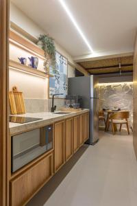 une cuisine avec des armoires en bois et un réfrigérateur en acier inoxydable dans l'établissement Beach Haus - Beira Mar - Let's AX Hospedagens, à João Pessoa