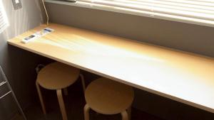 a counter with two stools under a counter top with a desk at Little Birds Hostel in Omihachiman