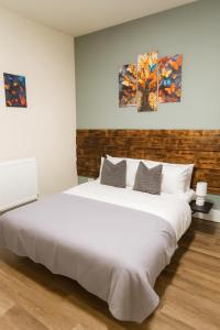 a white bed in a room with three paintings on the wall at City Stays Norwich in Norwich