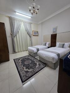 a hotel room with two beds and a rug at مسكن راحتك للشقق المخدومه in Tabuk +3 photos