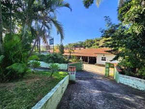 une allée en face d'une maison avec des palmiers dans l'établissement Pousada Refúgio Serrano, à Serra Negra