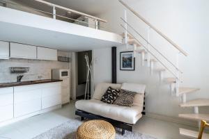 a living room with a couch and a staircase at Bright Loft Apartment Steps From Linnanmäki & Alppipuisto in Helsinki