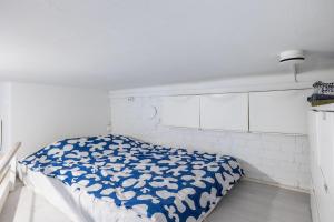 a bedroom with a bed with a blue and white comforter at Bright Loft Apartment Steps From Linnanmäki & Alppipuisto in Helsinki