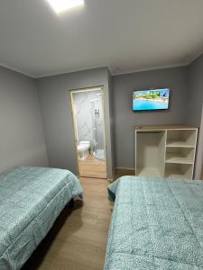 Un dormitorio con dos camas y un televisor en la pared. en Hotel RK, en Antofagasta