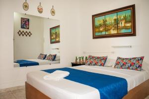 a bedroom with two beds with blue and white sheets at Hostal Kumbaya in Santa Marta