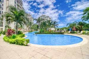 Una piscina en un complejo turístico con palmeras y edificios. en Jaco Bay, en Jacó