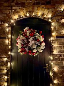 艾恩布里奇Ironbridge Tiny Hideaway的黑色大门上挂着圣诞花环，还有彩灯。