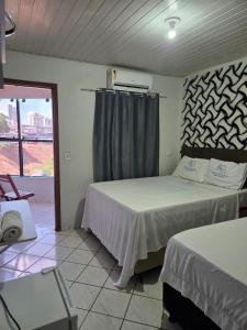 een slaapkamer met 2 bedden en een raam met uitzicht bij Hotel Danubio in Cuiabá