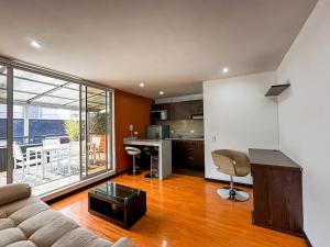 a living room with a couch and a kitchen at Hotel Regency Suites La Feria in Bogotá