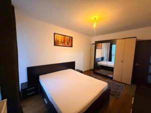 a bedroom with a white bed and a mirror at Modern apartment in Ford-Ferval area, Craiova in Craiova