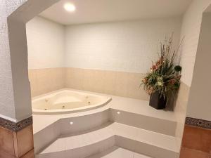 Un baño con bañera y un jarrón de flores. en Hotel Mirage Express, en Matamoros