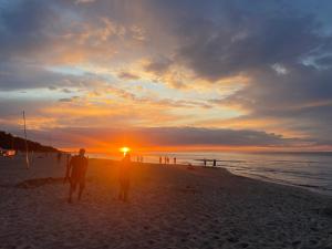 - deux personnes debout sur la plage au coucher du soleil dans l'établissement P20 apartament, à Sztutowo