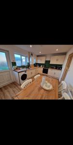 The Cosy House في ويلينغتون: مطبخ مع خزائن بيضاء وطاولة وكراسي