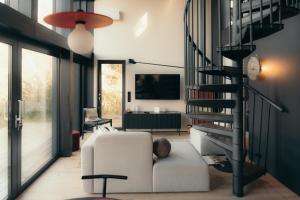a living room with a white couch and a spiral staircase at Īves, Koka Maja in Amatciems