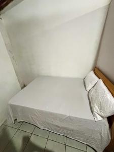 a small white bed in a corner of a room at Casa em Itacaré no Centro, ao lado da Pituba in Itacaré