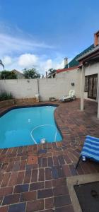 a swimming pool on a brick patio with a blue bench at 18 Laburnum Lodge in Durban