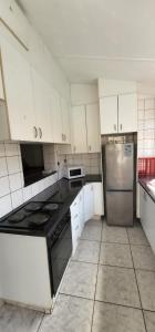 a kitchen with white cabinets and a stainless steel refrigerator at 18 Laburnum Lodge in Durban