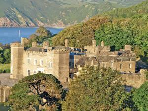 eine Burg auf einem Hügel neben dem Wasser in der Unterkunft Watermouth Castle, Harbour Apartment in Ilfracombe