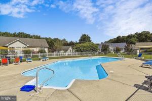 a swimming pool in a yard with chairs and tables at Spacious Home Bethany Beach in Frankford