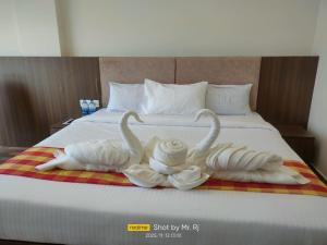 Dos cisnes están hechos de toallas en una cama. en R2B Grand Hotel, en Kolār