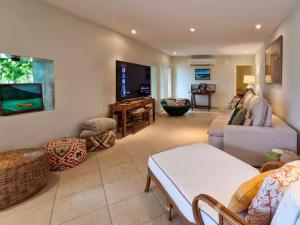 a living room with a couch and a tv at NOVO Mansão Pé na Areia com Heliponto, 1 Piscina, 1 Hidro, Sauna e 5 Quartos in Angra dos Reis