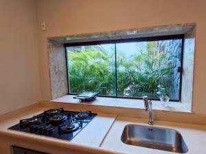 a kitchen with a stove and a sink and a window at NOVO Mansão Pé na Areia com Heliponto, 1 Piscina, 1 Hidro, Sauna e 5 Quartos in Angra dos Reis