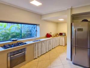 a kitchen with a large window and a stainless steel refrigerator at NOVO Mansão Pé na Areia com Heliponto, 1 Piscina, 1 Hidro, Sauna e 5 Quartos in Angra dos Reis