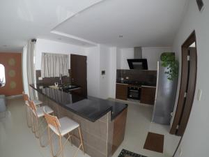 eine Küche mit einer Bar mit Stühlen und einer Arbeitsplatte in der Unterkunft Serenity Palmas- in Santa Cruz de la Sierra