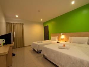 a hotel room with two beds and a green wall at T Hotel Kuala Perlis in Kuala Perlis