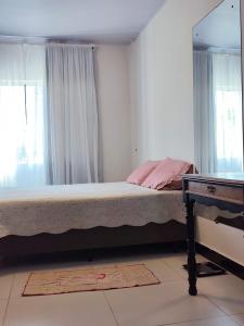 une chambre avec un lit avec un miroir et un bureau dans l'établissement Suíte Ampla Ideal para Família, à Garopaba