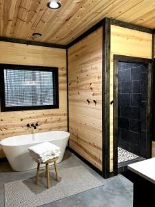 La salle de bains en bois est pourvue d'une baignoire et d'une douche. dans l'établissement The Stunning Shady Creek Cabin, à Broken Bow 25 autres photos