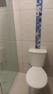 une salle de bain avec des toilettes blanches et une douche dans l'établissement Suíte Ampla Ideal para Família, à Garopaba