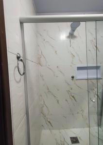 La salle de bains est pourvue d'une douche et d'un mur en marbre. dans l'établissement Suíte Ampla Ideal para Família, à Garopaba