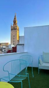 Un banco y un sofá en un balcón con una torre del reloj en Lukanda Hospec Olehousing, en Sevilla