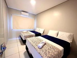 ein Hotelzimmer mit zwei Betten und einem Fenster in der Unterkunft Casa 01 - Casa com 2 quartos, próximo a rodoviária e aeroporto in Palmas