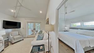 une chambre blanche avec un lit et une chaise dans l'établissement Crystal Blue Persuasion, à Santa Rosa Beach