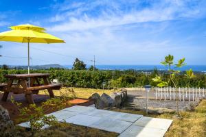 a picnic table with a yellow umbrella on a patio at Jeju Starlight Glamping in Jeju
