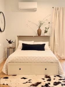 a bedroom with a white bed and a clock on the wall at Hillside Haven | Boutique Spanish Escape in Ojai +23 photos