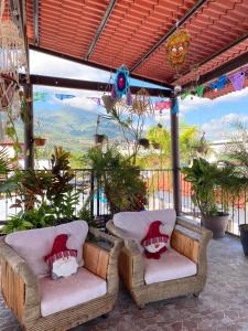 two wicker chairs sitting on a porch with a view at Grann Posada Xilitla in Xilitla