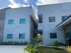 a large white building with green windows at Sanzé Flats - São José da C Grande in São José da Coroa Grande