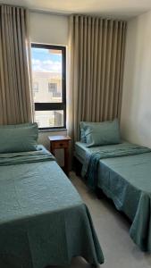 a hotel room with two beds and a window at Seu Descanso a Beira Mar in Ilhéus +39 photos