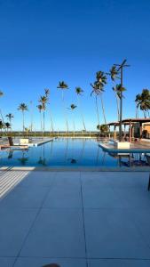 a swimming pool with palm trees in the background at Seu Descanso a Beira Mar in Ilhéus