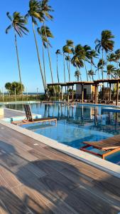 a swimming pool with palm trees in the background at Seu Descanso a Beira Mar in Ilhéus