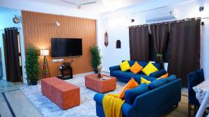 ein Wohnzimmer mit blauen Sofas und einem Flachbild-TV in der Unterkunft Emaar Homestays in Hyderabad